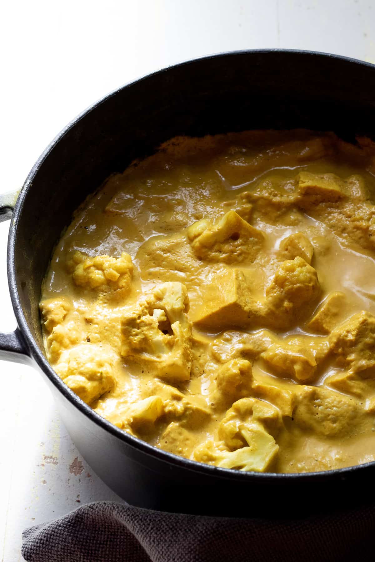 large black pot of yellow curry with gray cloth 