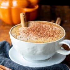 latte in white mug with pumpkin pie spice on wooden table
