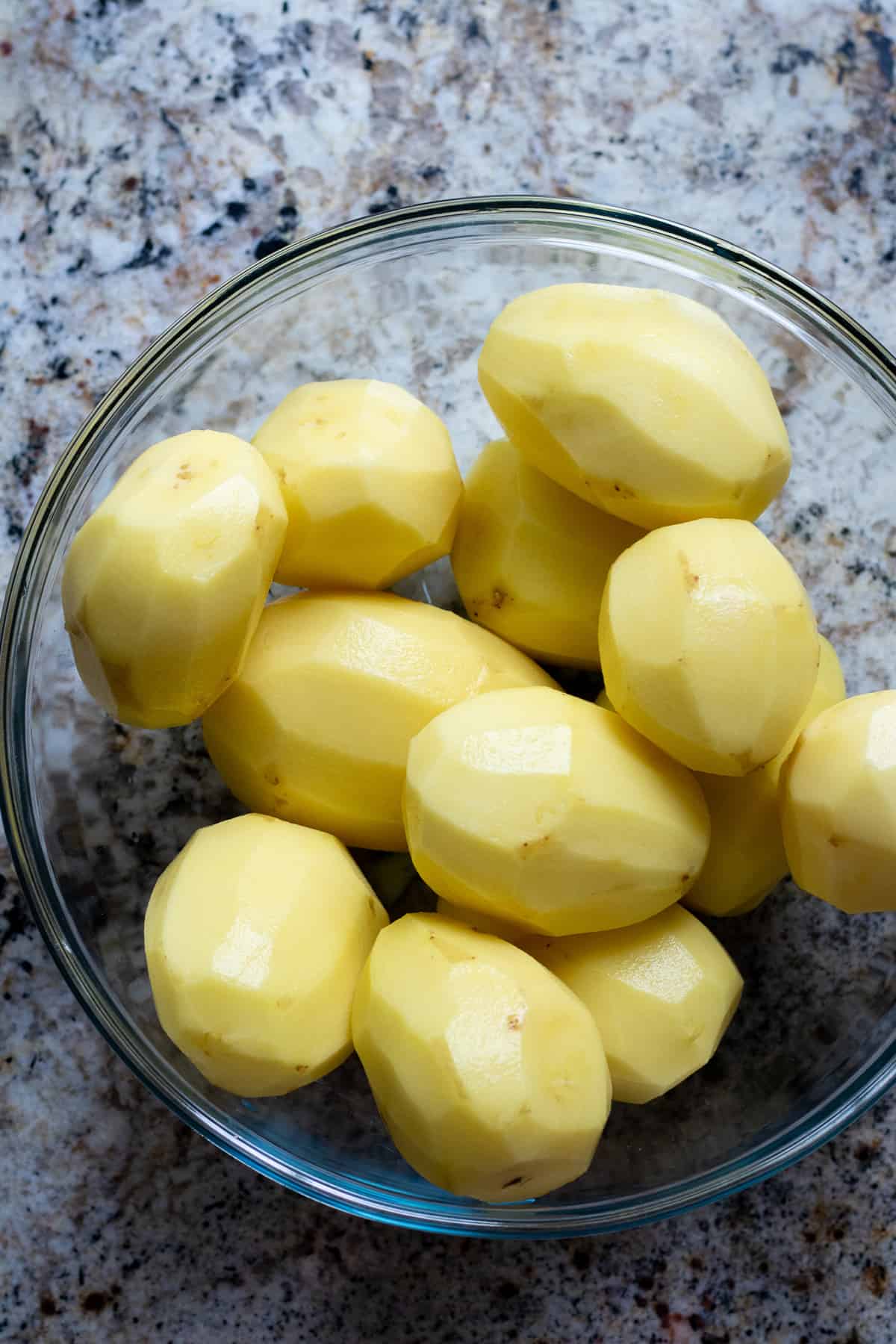 Peeled gold potatoes in a glass bowl.