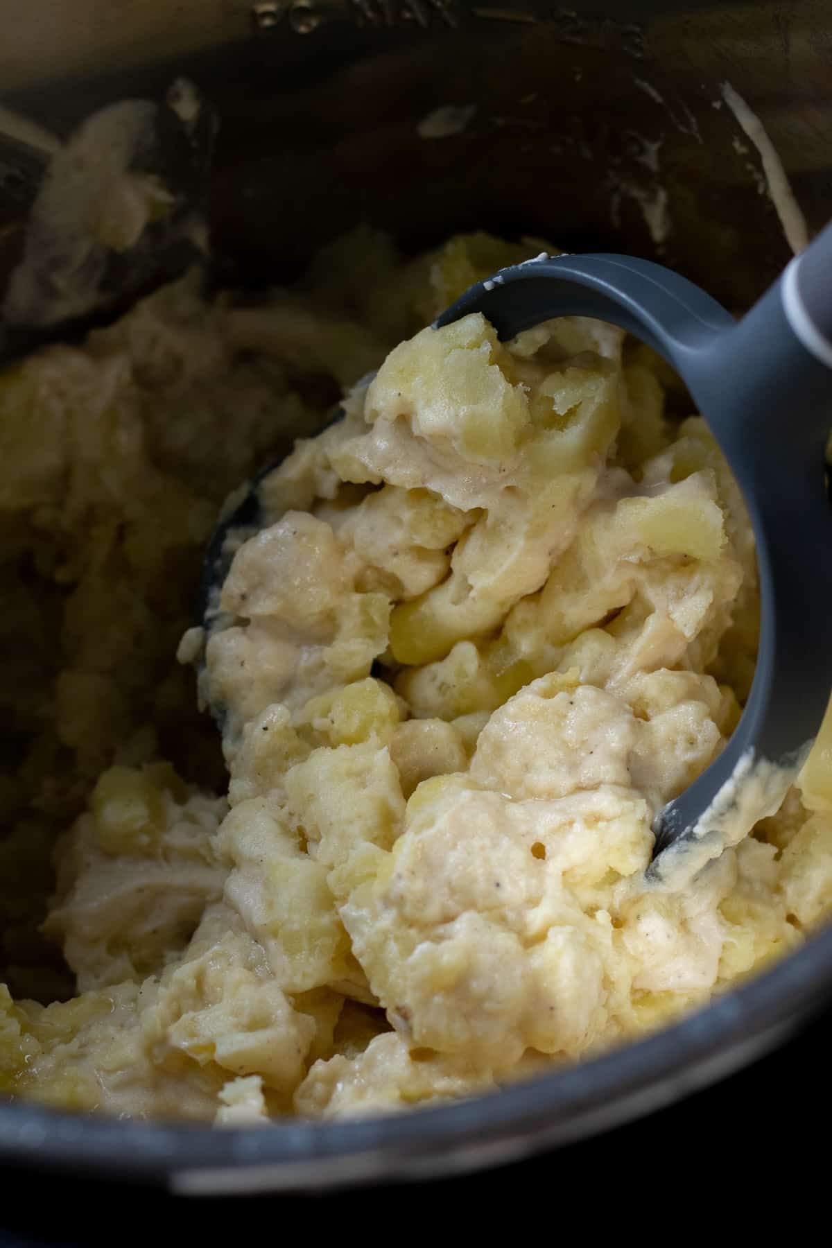 Mashing the potatoes with a potato masher.
