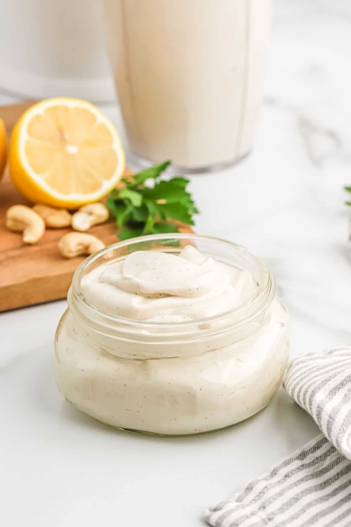 Sour cream in glass jar with garnish in background.