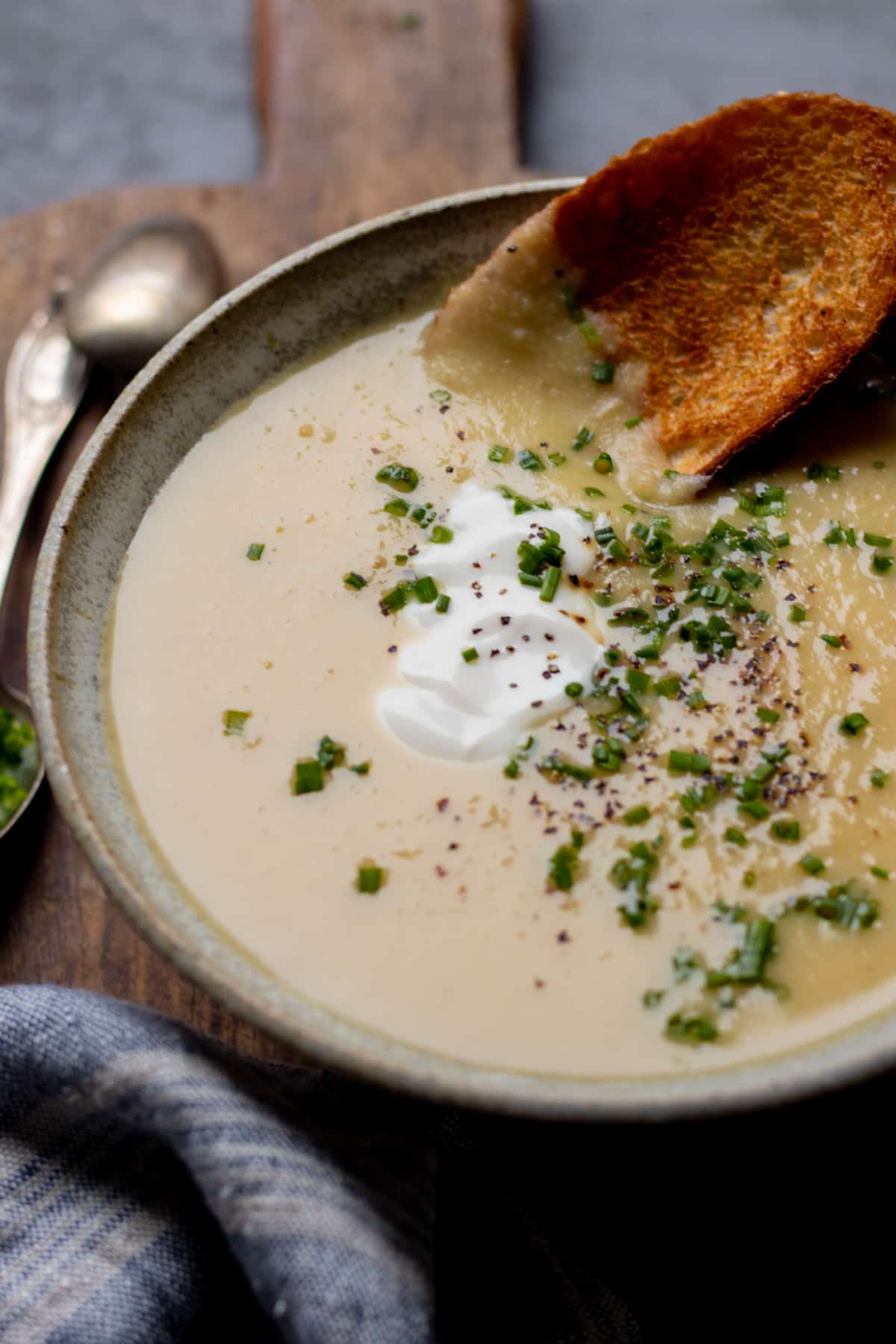 Bowl of soup topped with chives, pepper, and yogurt.