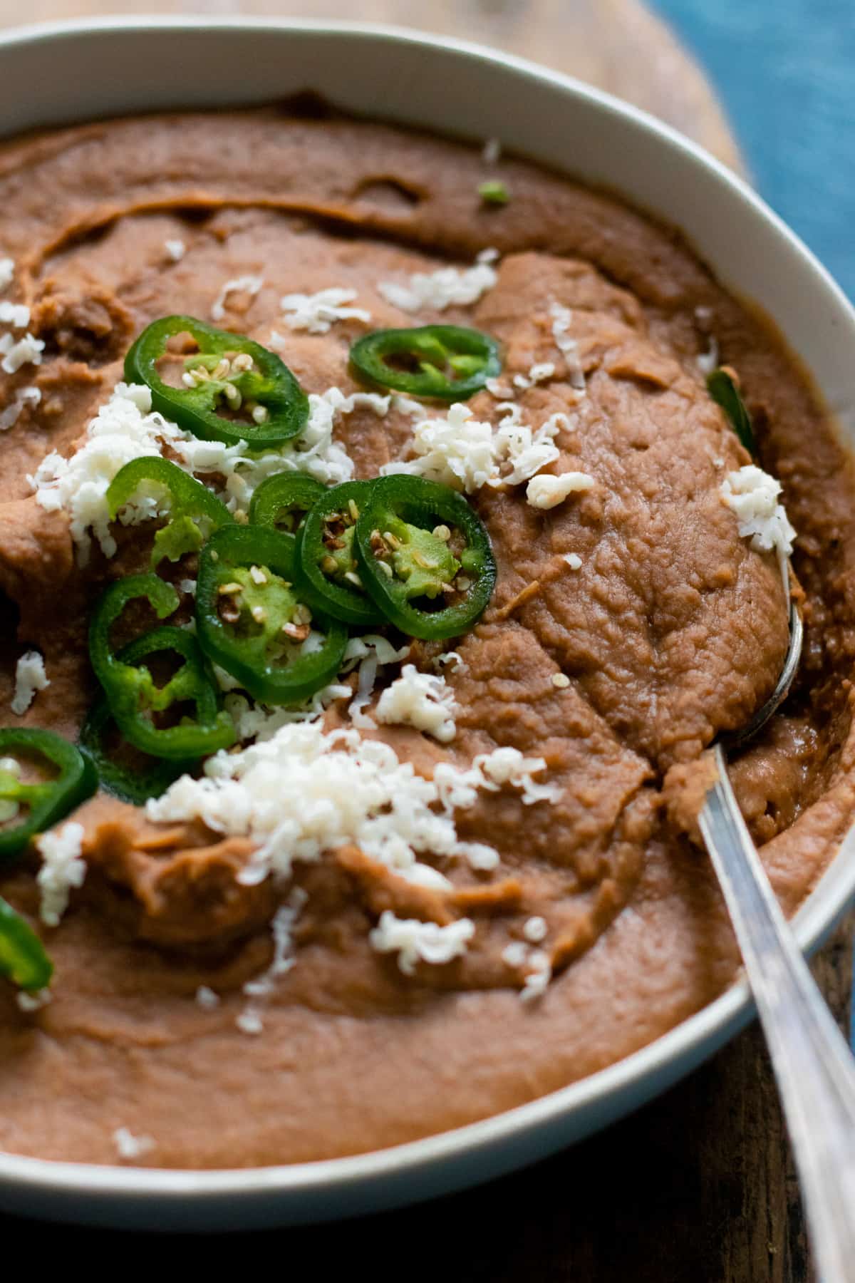 Close up of refried beans with spoon in bowl.