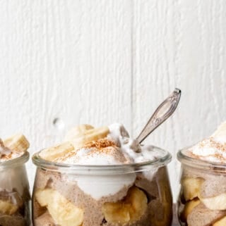Three glass jars filled with pudding and topped with whipped cream.