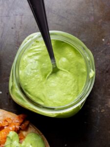Avocado crema in glass jar with spoon.