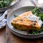 Frittata on plate with arugula and dollop of vegan sour cream.