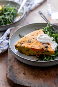 Frittata on plate with arugula and dollop of vegan sour cream.