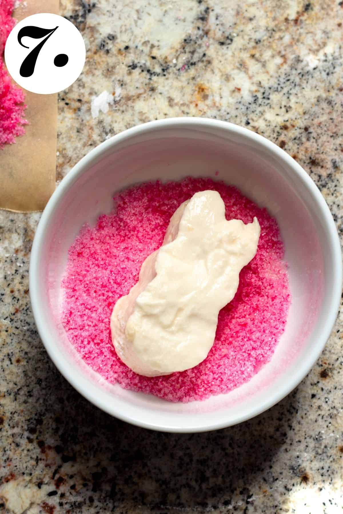 White marshmallow peep on top of pink sugar before being coated.