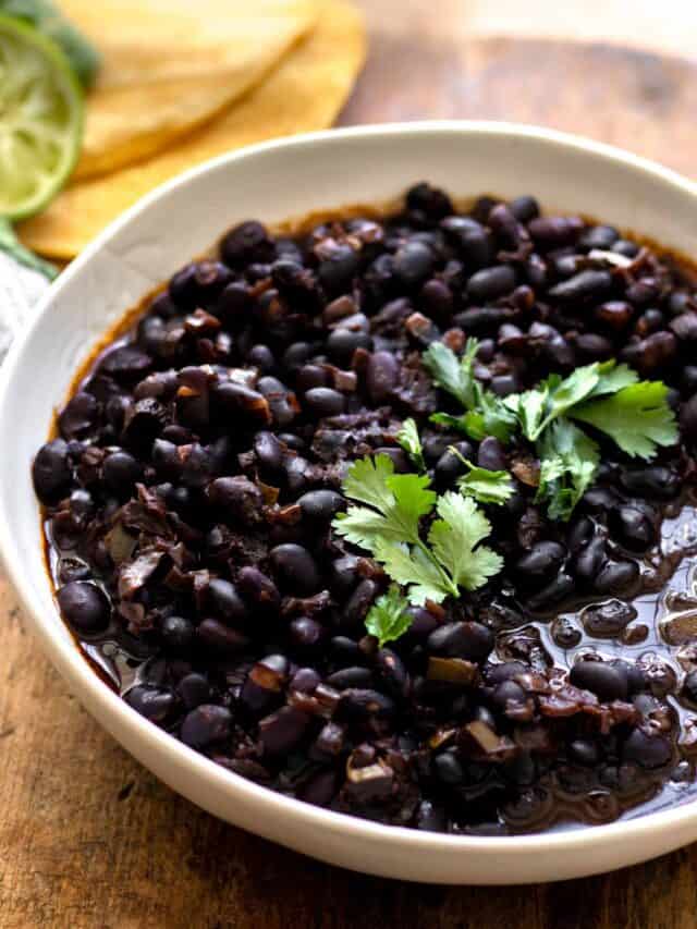 Cooked beans in white bowl garnished with cilantro.