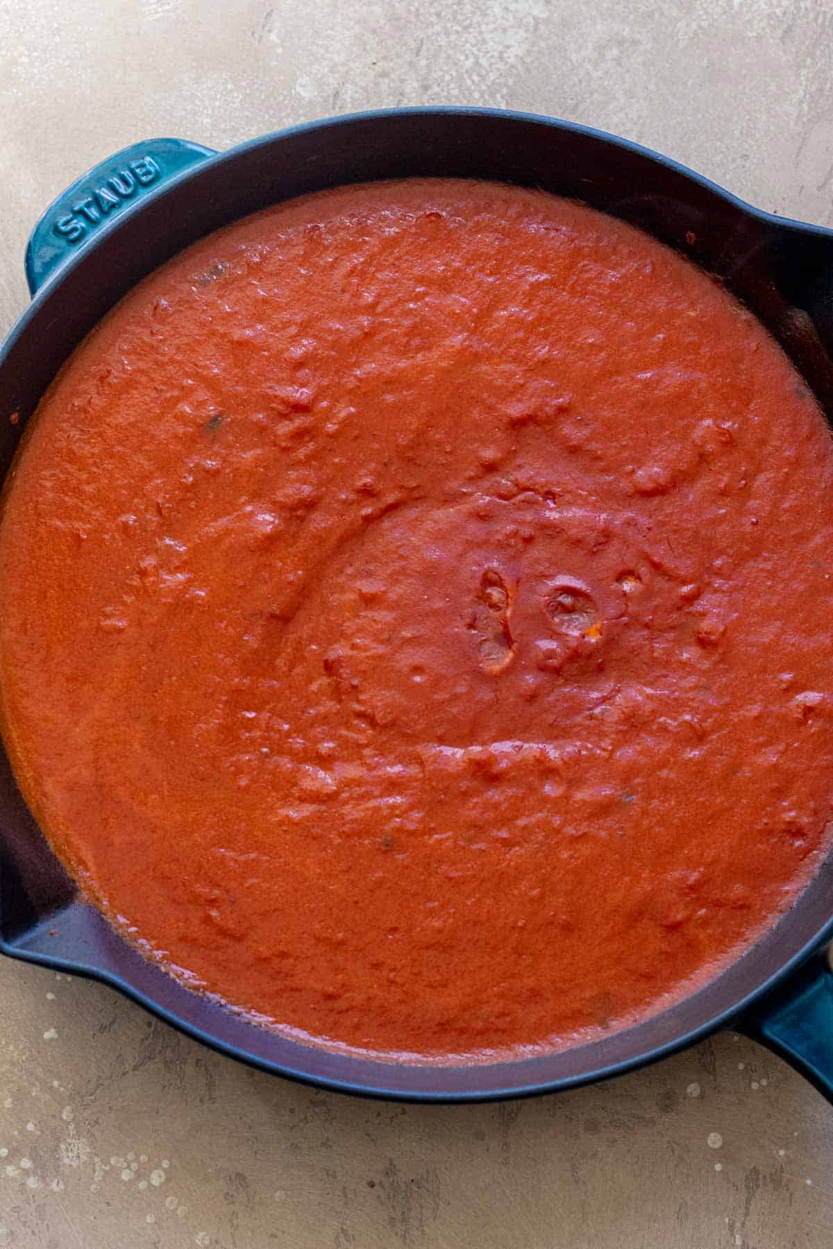 Marinara and oat milk mixed together in blue cast iron skillet.