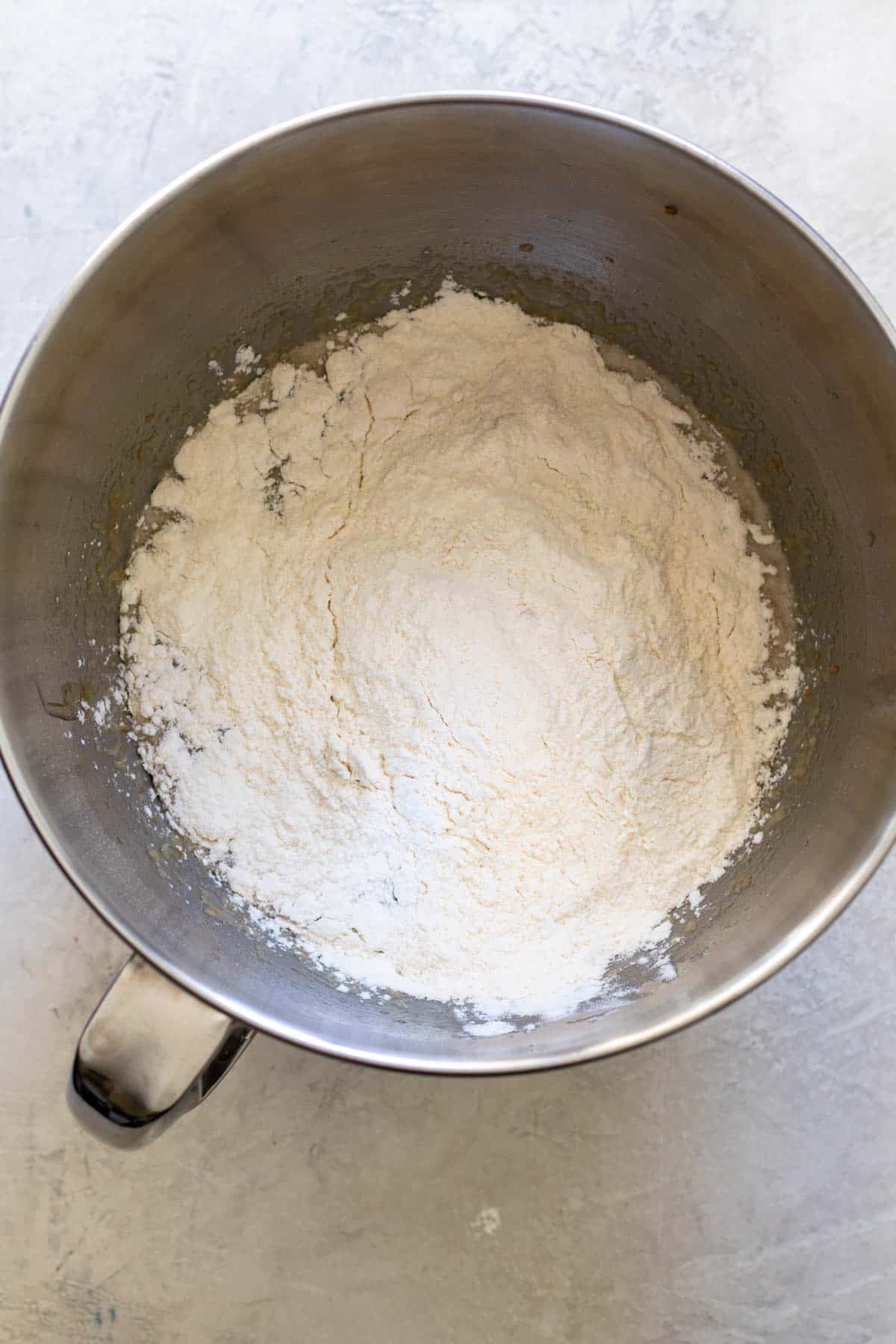 Flour and dry ingredients added overtop wet ingredients in large mixing bowl.