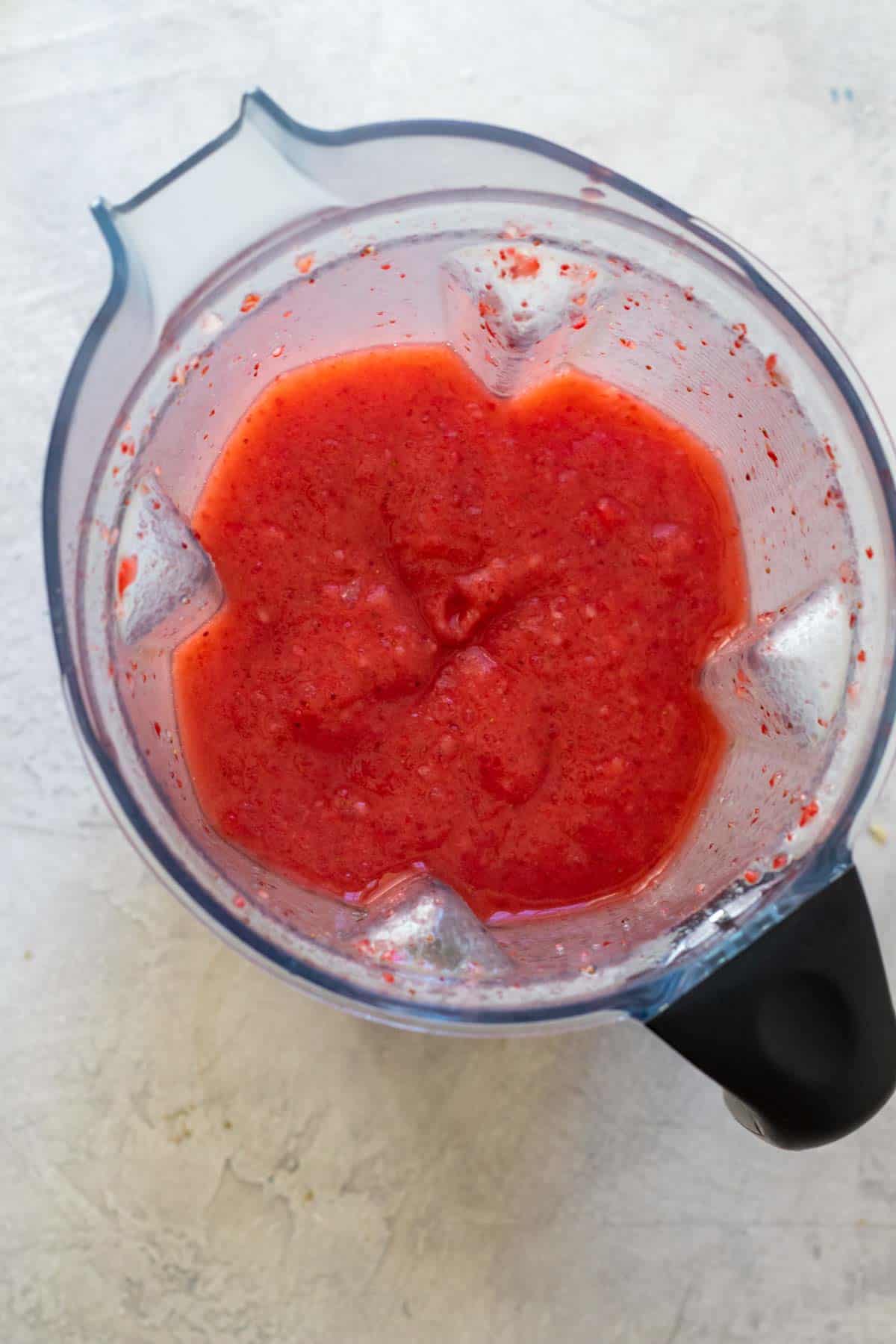 Frozen strawberries, crushed ice, tequila, lime juice and agave in blender after blending.