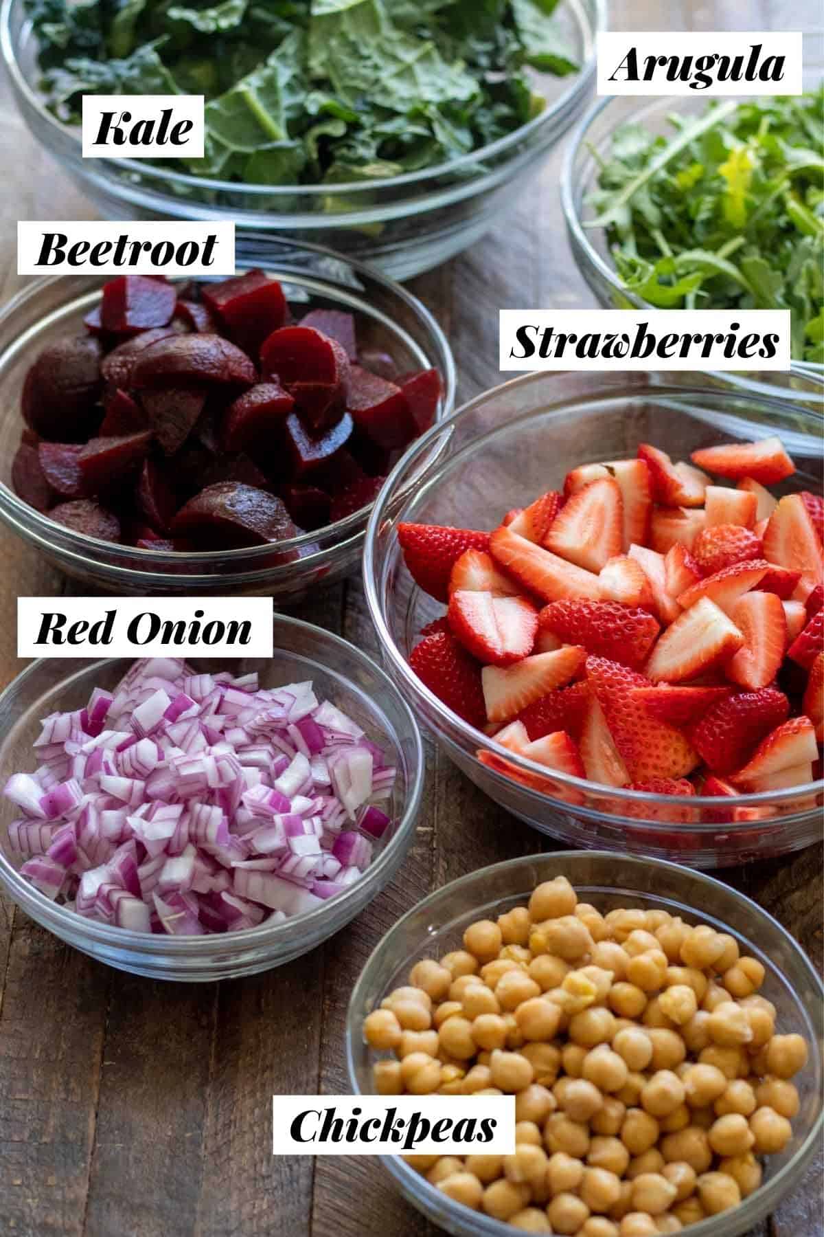Main salad ingredients measured out into individual glass bowls and labeled.