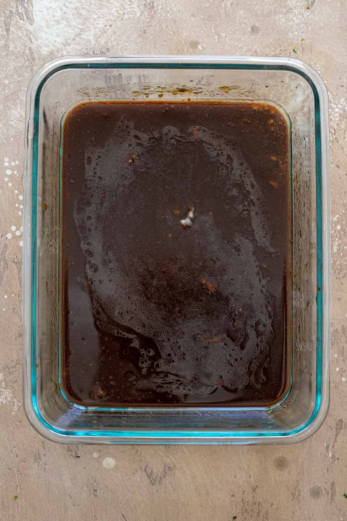 Hoisin sauce, water, garlic, low-sodium tamari mixed together in shallow glass dish.