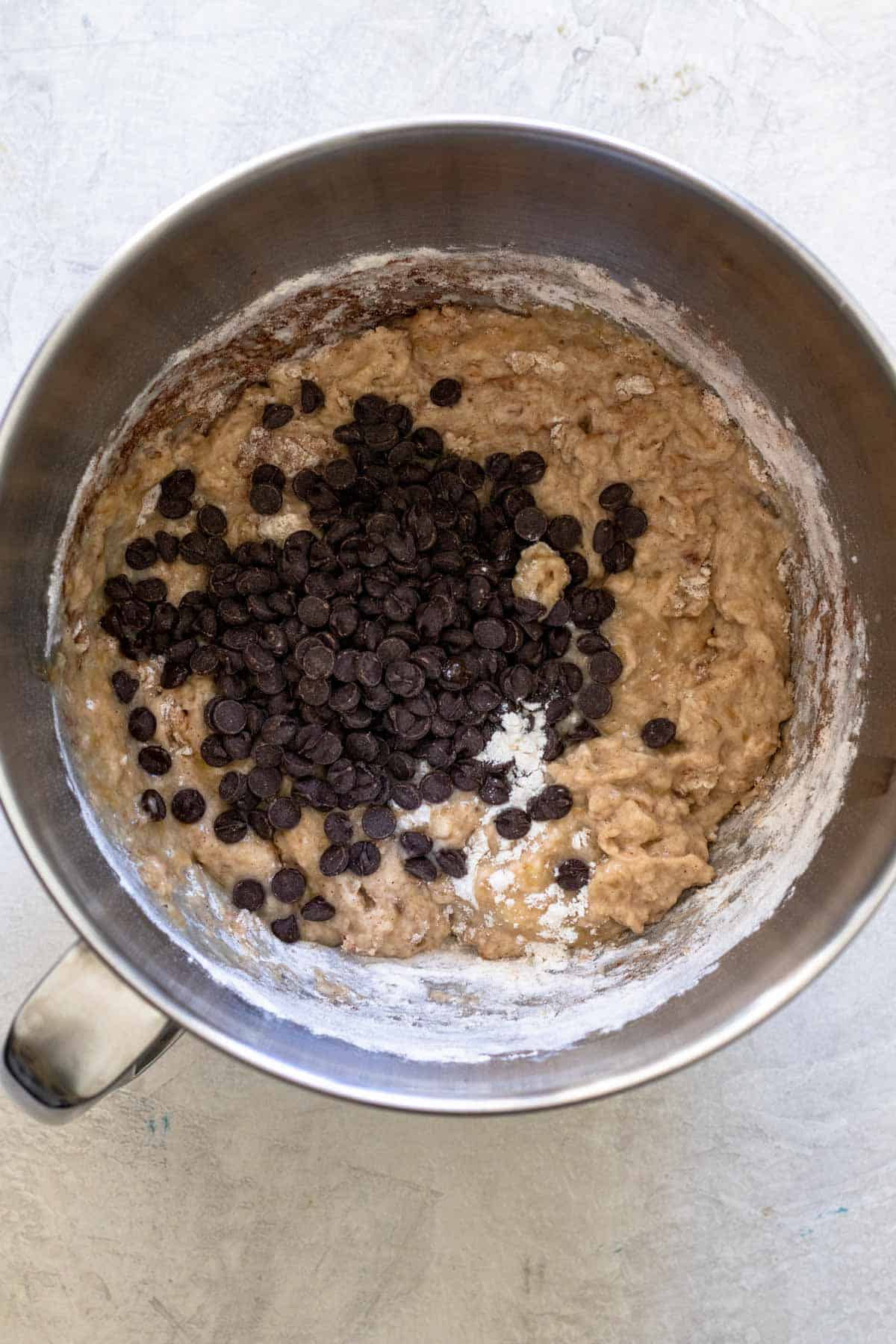 Vegan chocoalte chips added into banana bread batter in mixing bowl.