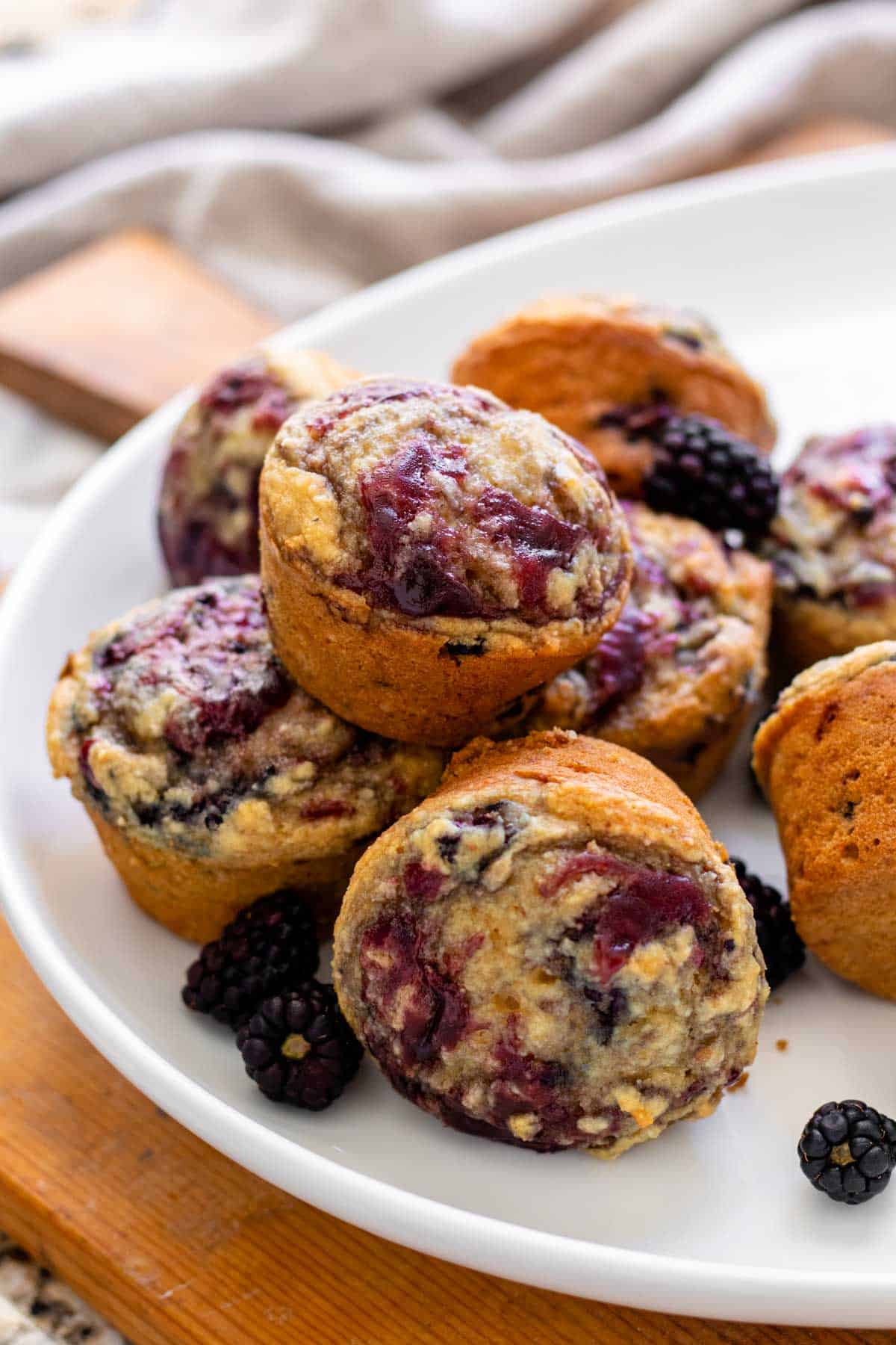 Muffins on white serving tray with fresh blackberries.