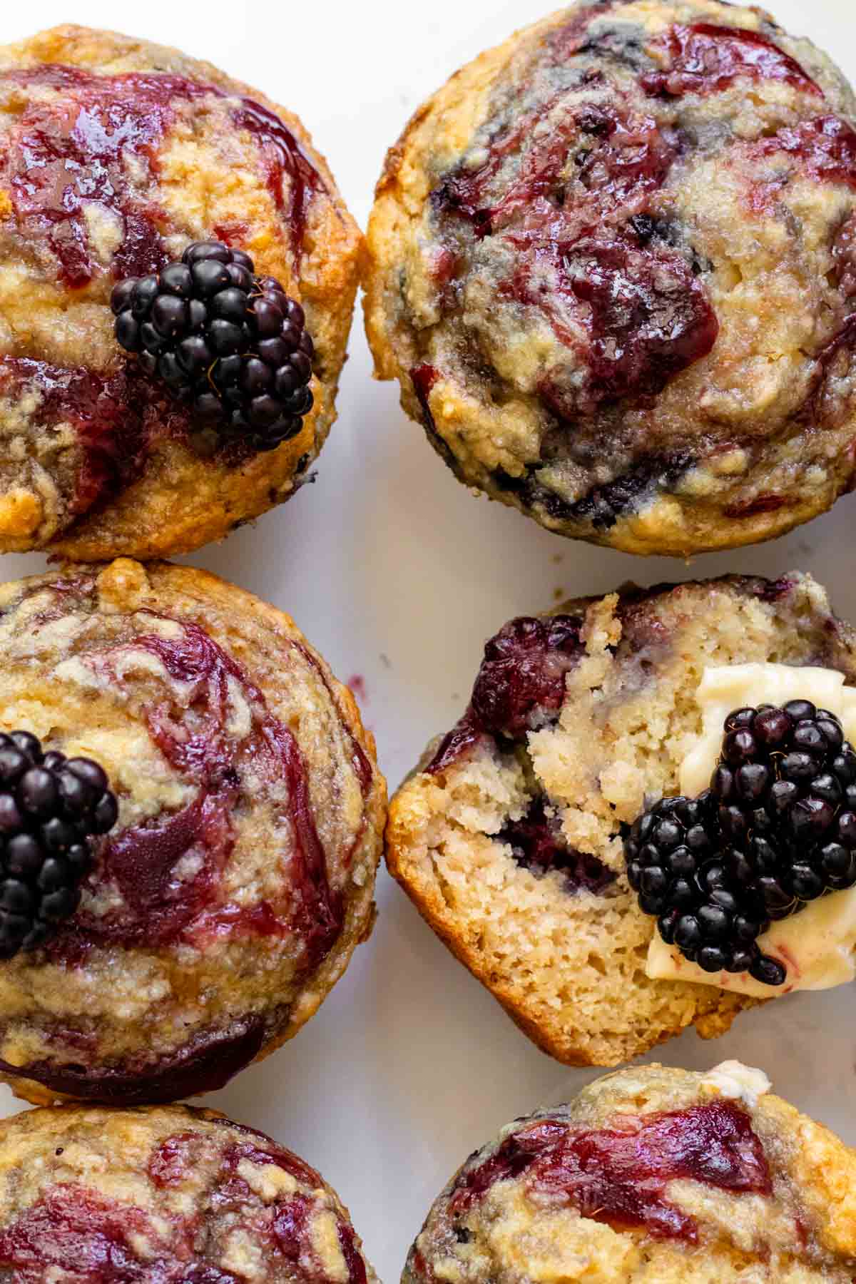 Closeup of 6 muffins with 1 cut in half exposing texture of muffin.