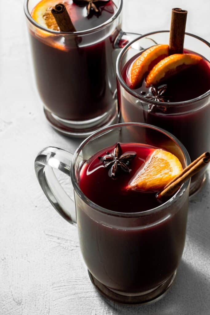 3 glass mugs full of non-alcoholic mulled wine on gray background.