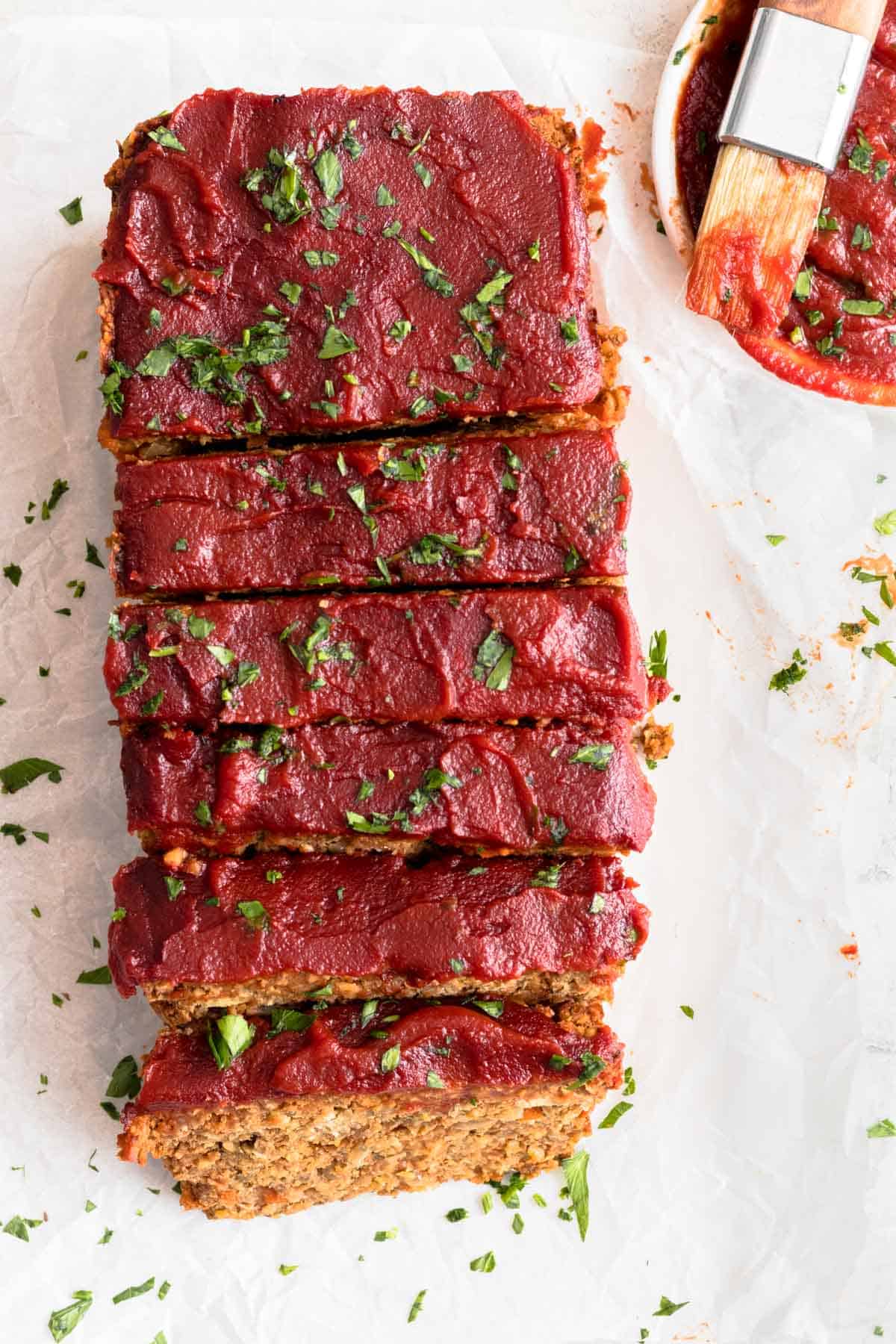 Sliced meatloaf on parchment paper and topped with parsley.