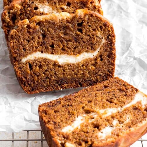 Slices of pumpkin banana bread on white parchment paper and cooling rack.