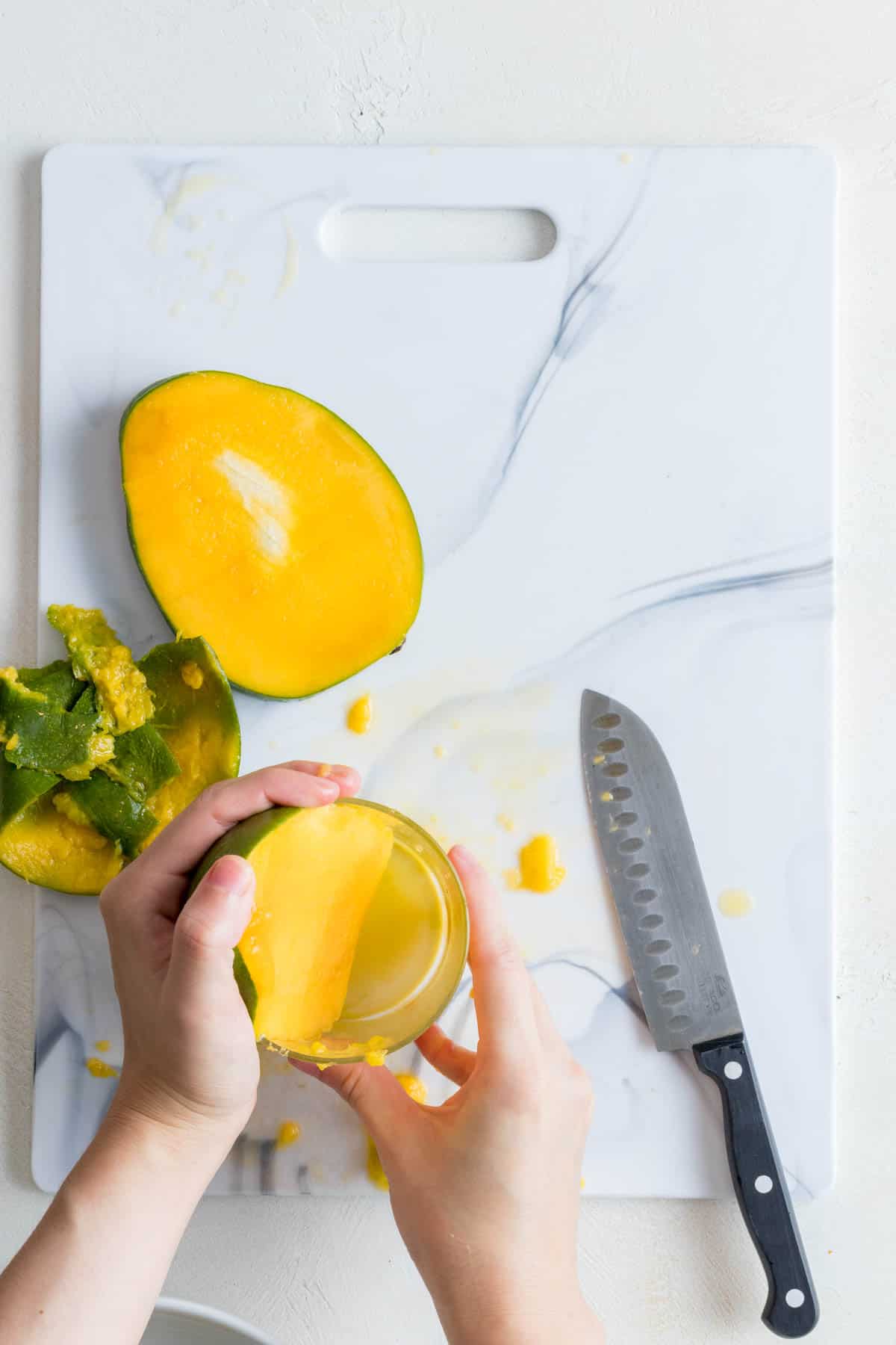 Pushing mango down on the glass.