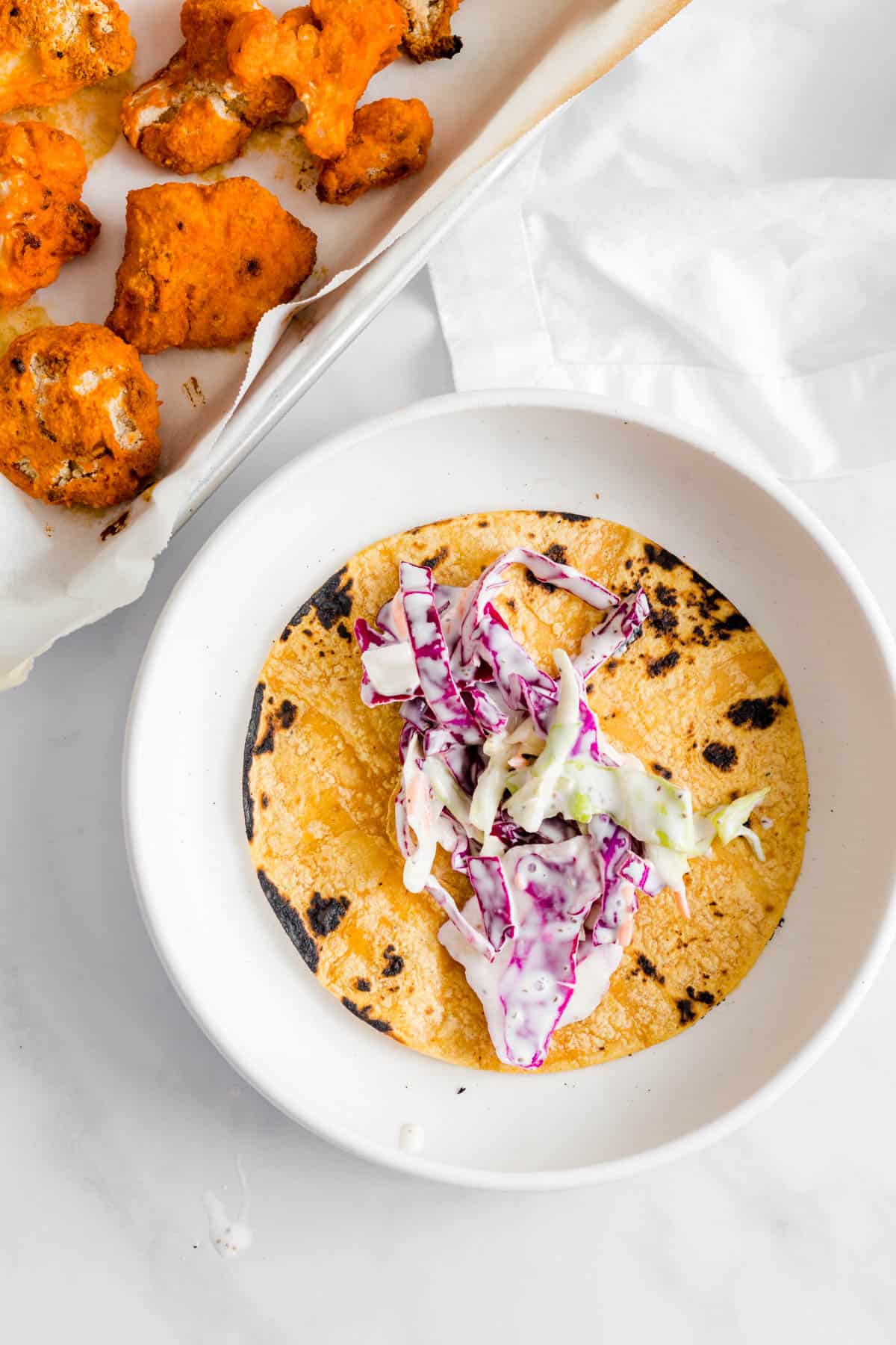 Coleslaw added to charred tortilla.