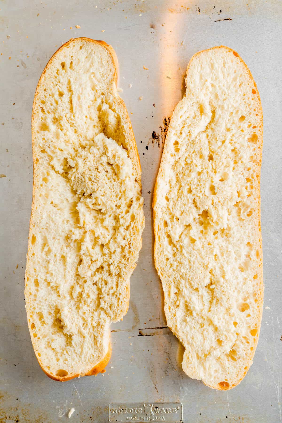 Italian bread sliced in half long ways and placed on a baking sheet.