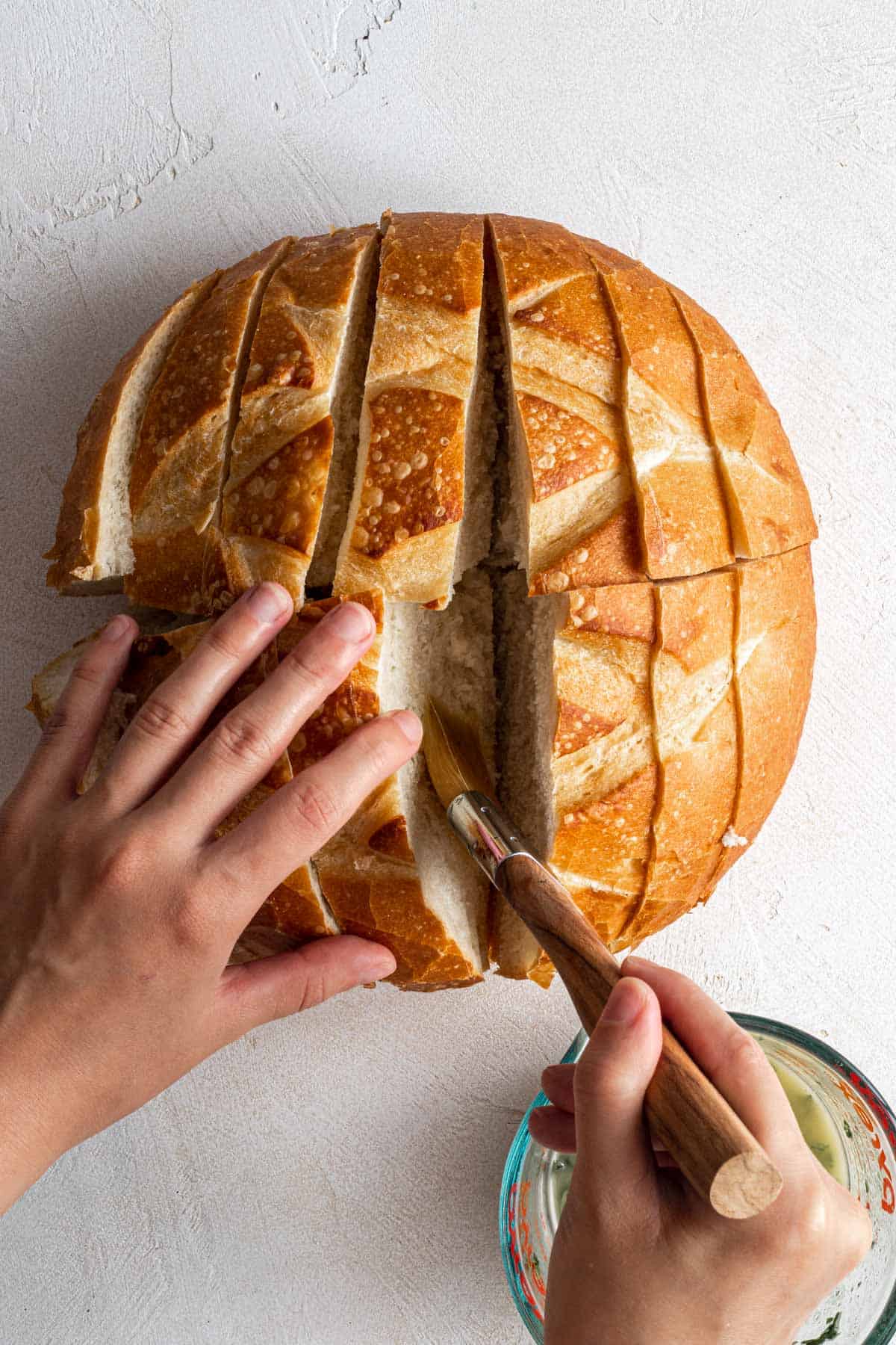 Brushing the bread with vegan garlic butter.