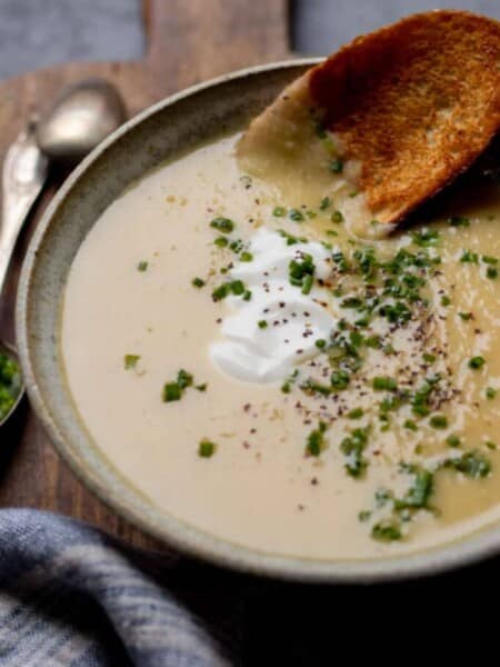 Bowl of soup topped with chives, pepper, and yogurt.