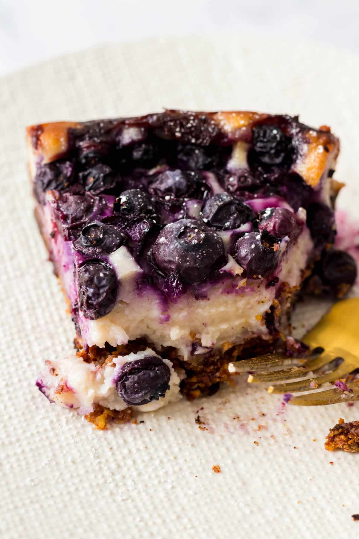 Slice of blueberry cheesecake with bites taken out.
