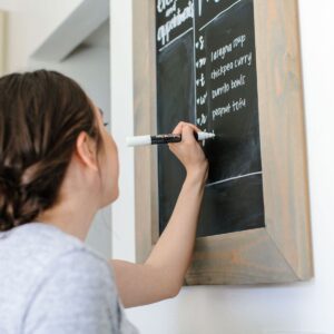 Girl writing meal plan on chalkboard.