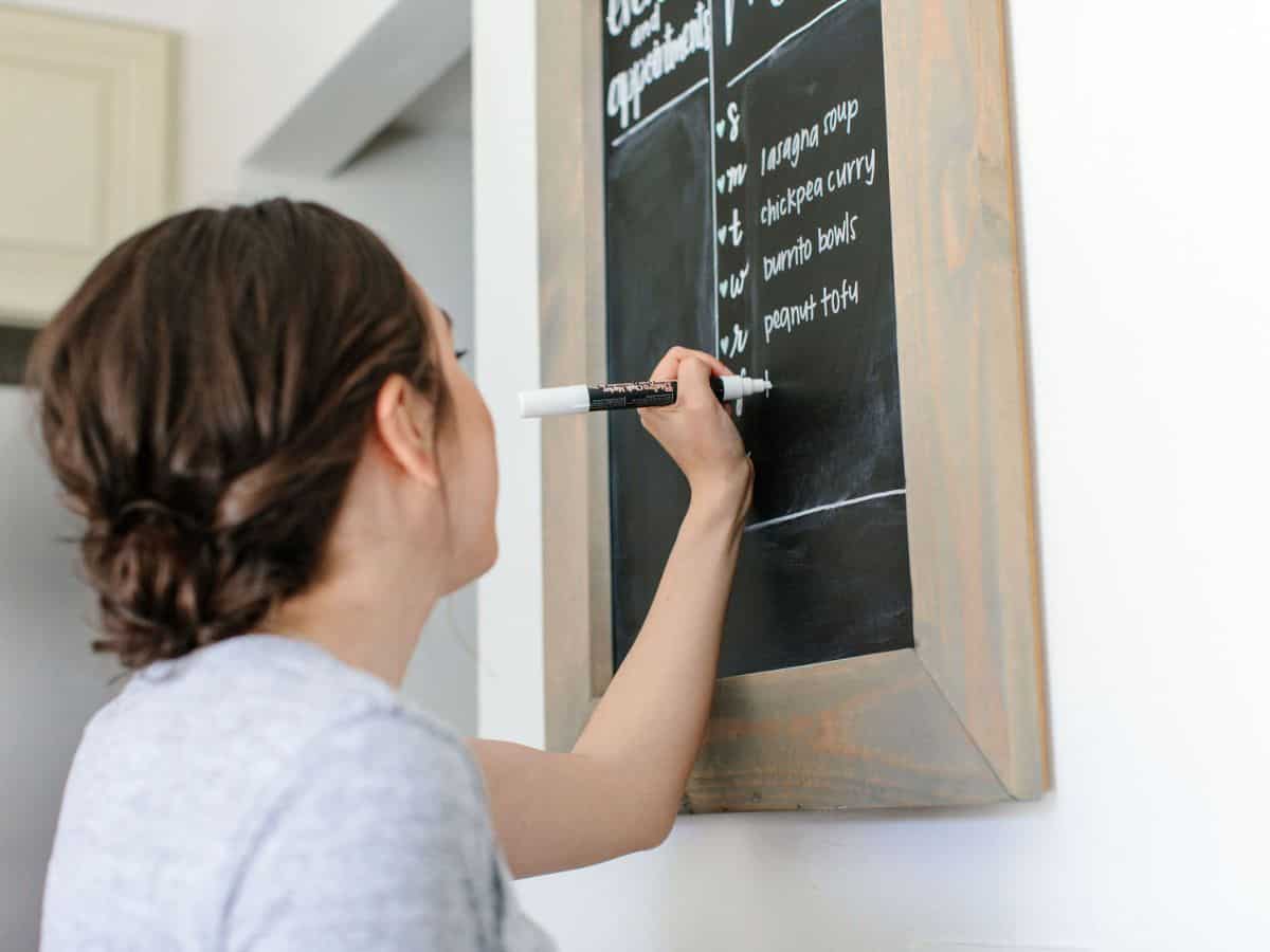 Girl writing meal plan on chalkboard.