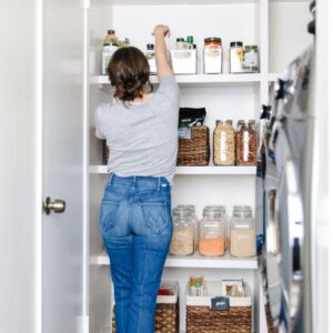Girl in pantry reaching for item.