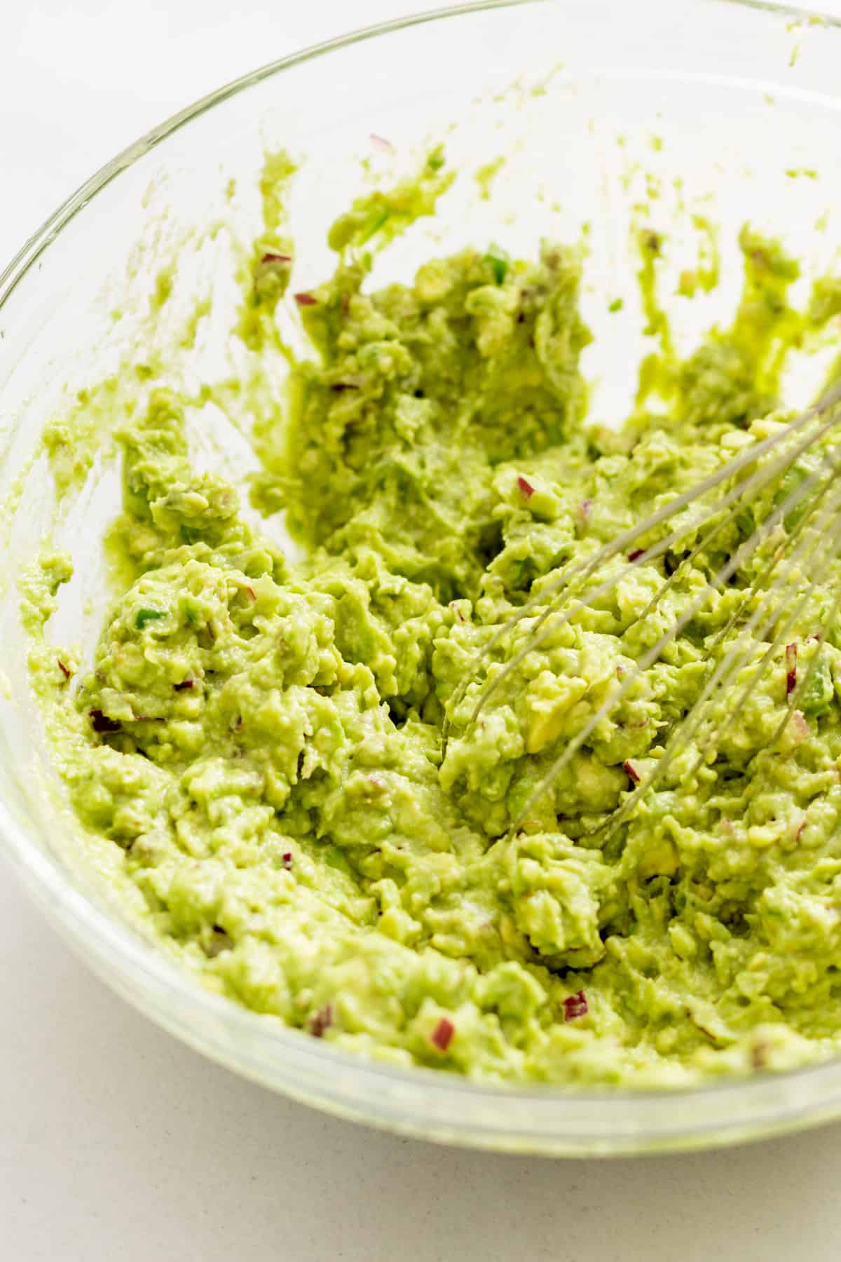 Using a whisk to mash the guacamole.