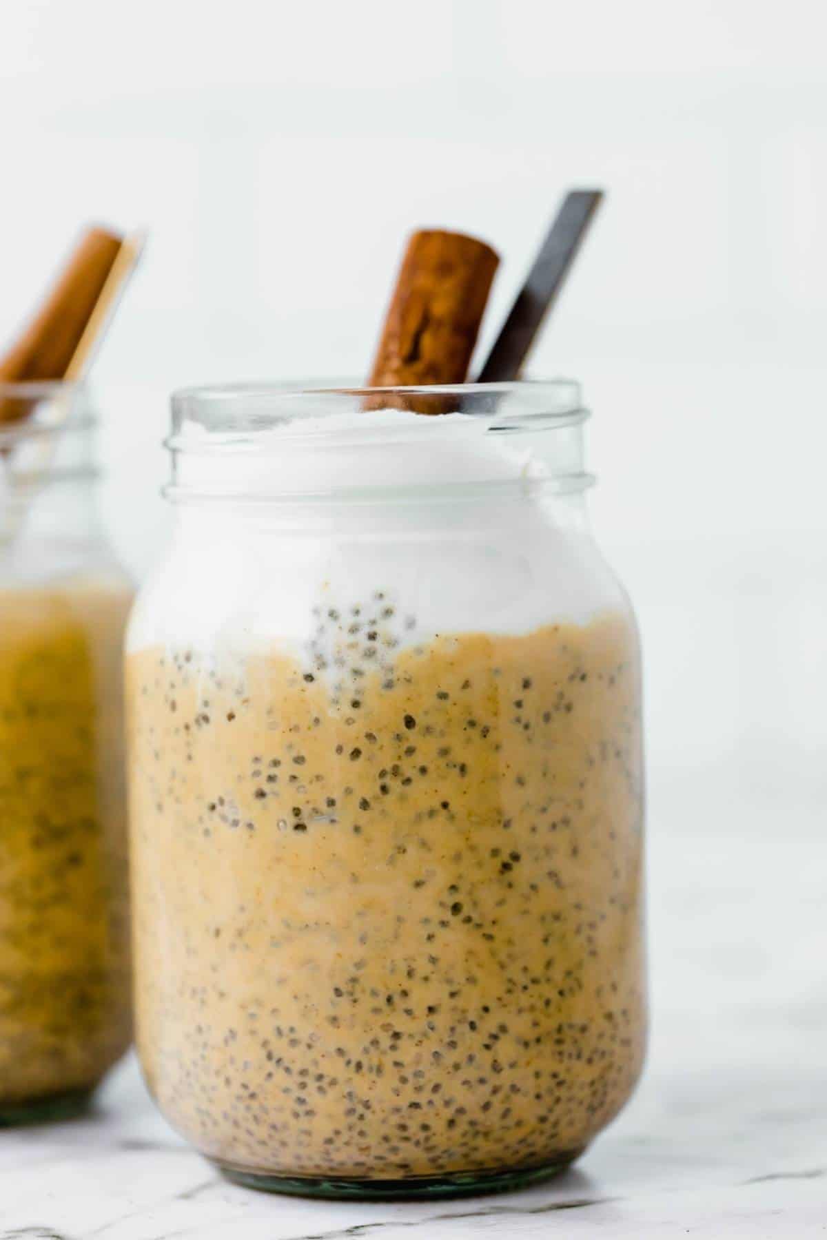 Closeup of pumpkin chia pudding with coconut whip and cinnamon stick.