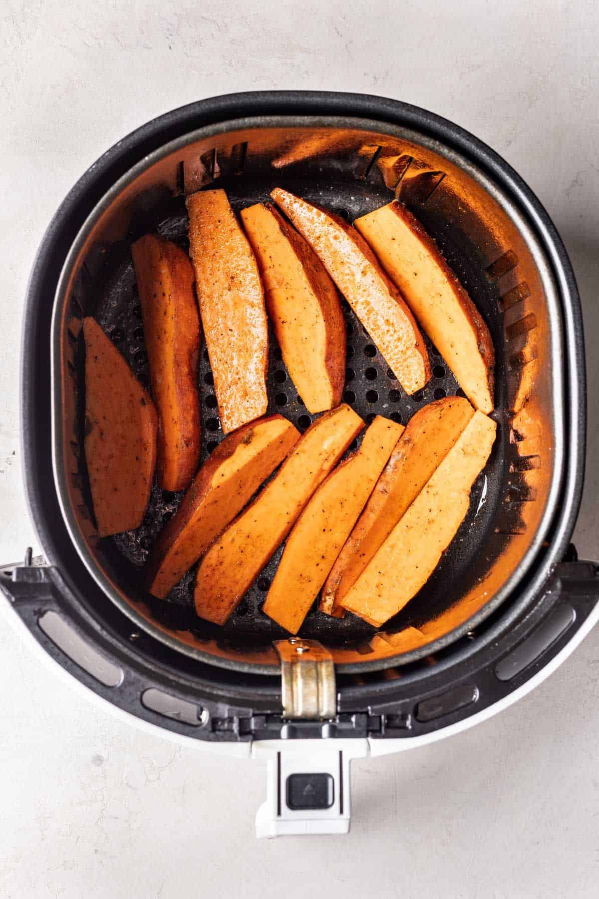 Uncooked sweet potato wedges in the air fryer.