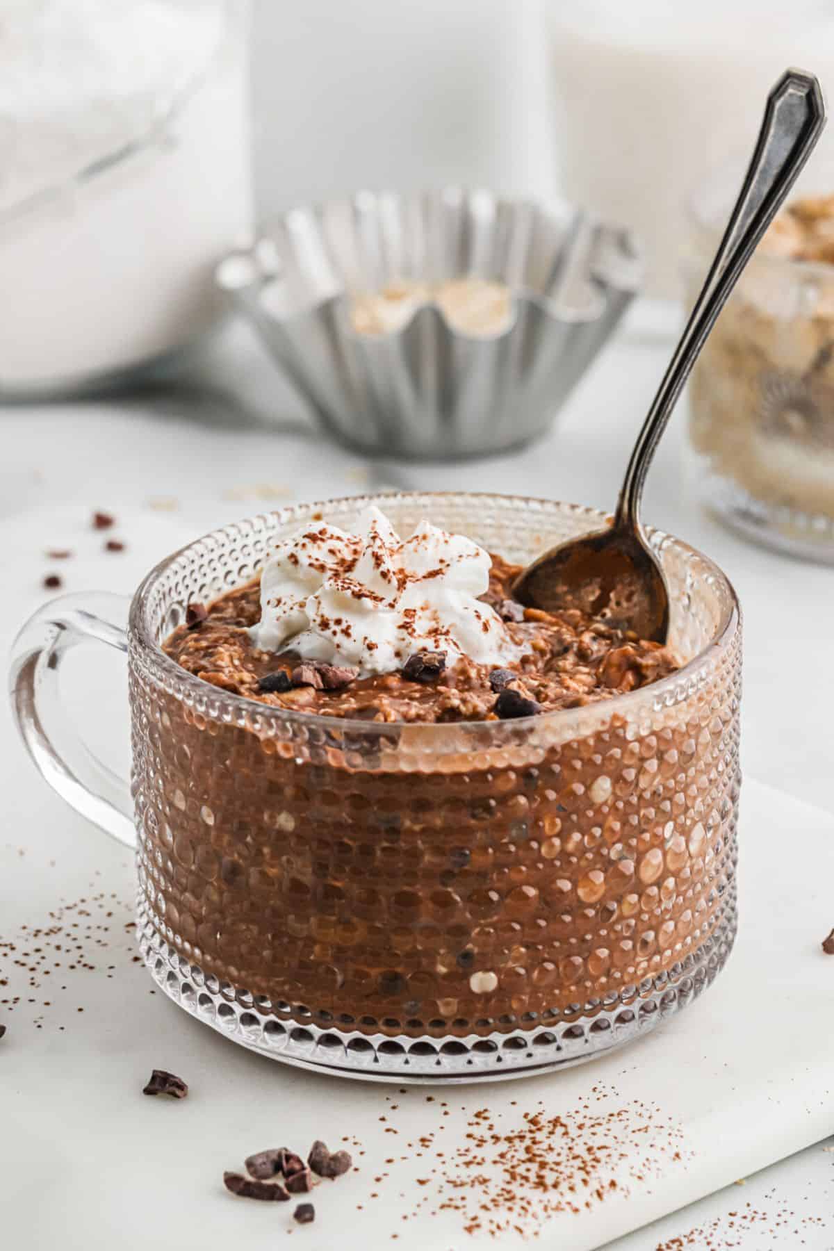 Oats in glass topped with whipped cream and garnished with chocolate.