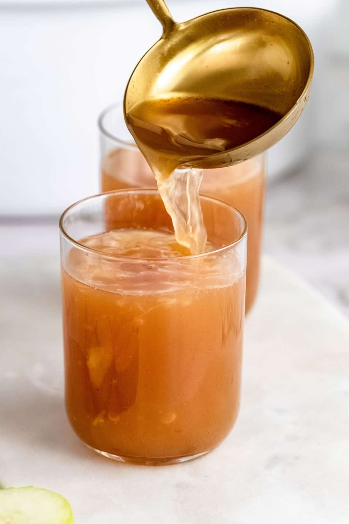Pouring apple cider in drinking glass.