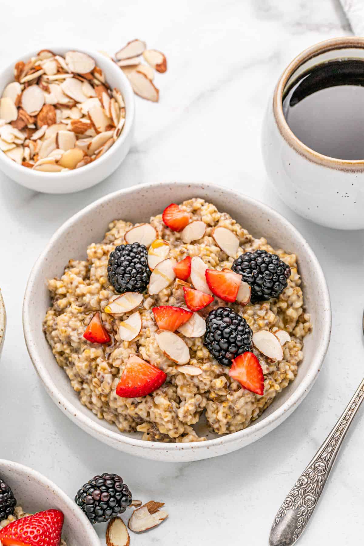 Bowl of oats with berries and cup of coffee.