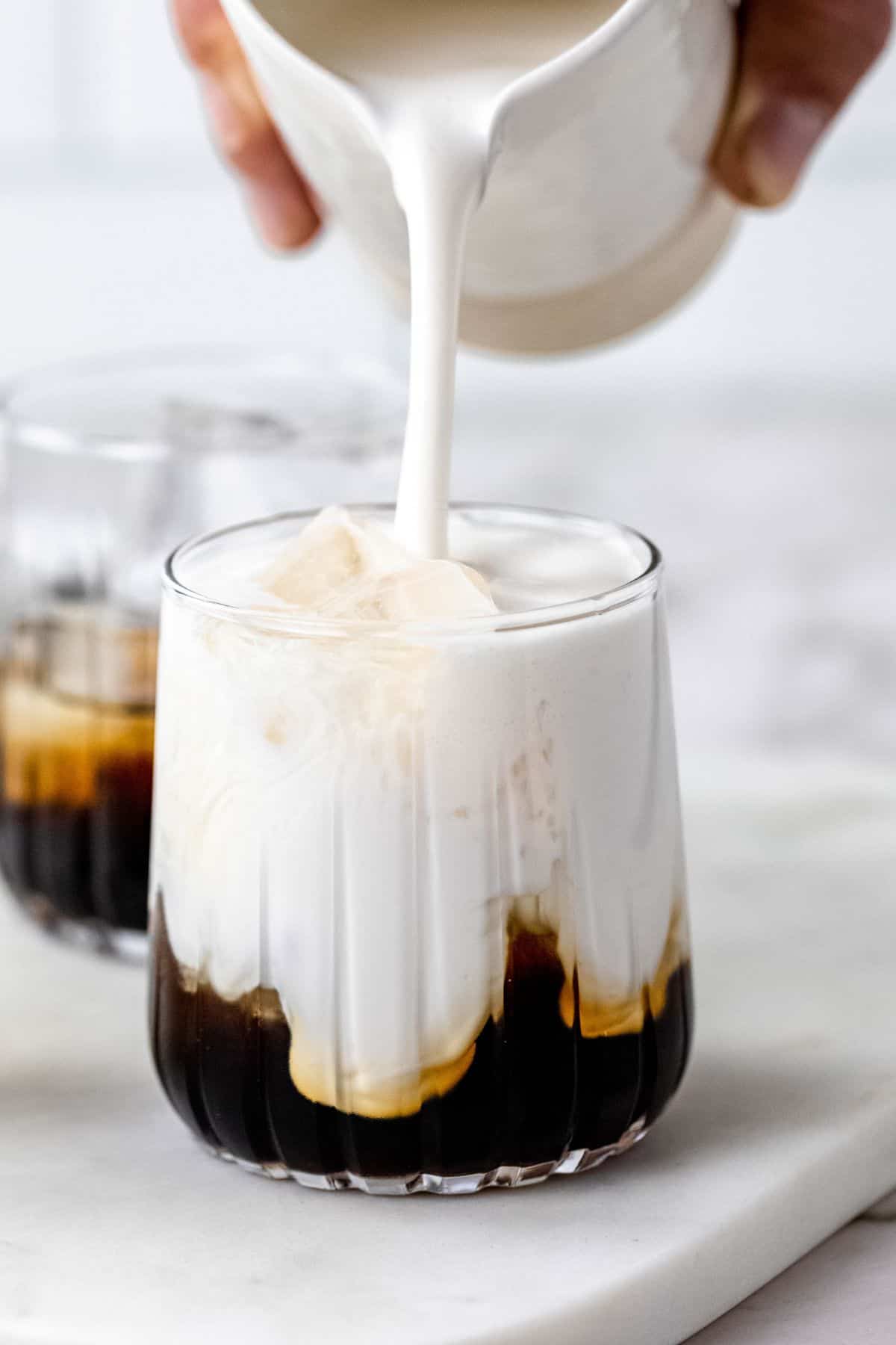 Pouring coconut milk over kahlua and vodka.