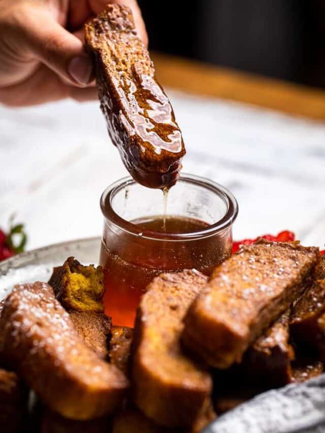 Dipping french toast stick into maple syrup.