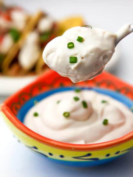 Vegan sour cream on spoon with chives.