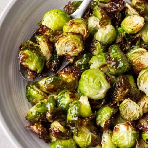 Bowl of crispy air fryer Brussels sprouts with a spoon.
