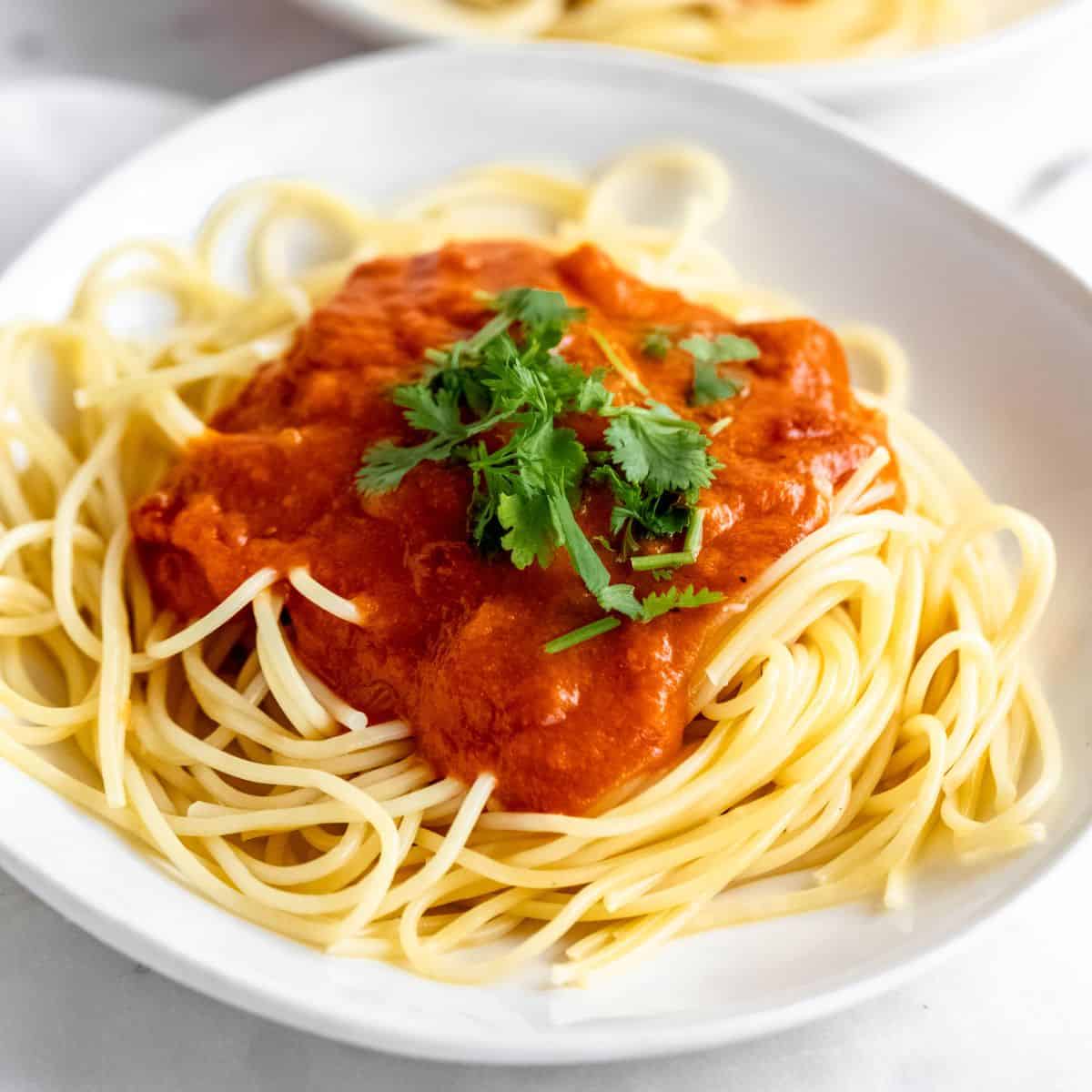Bowl of spaghetti topped with marinara sauce.