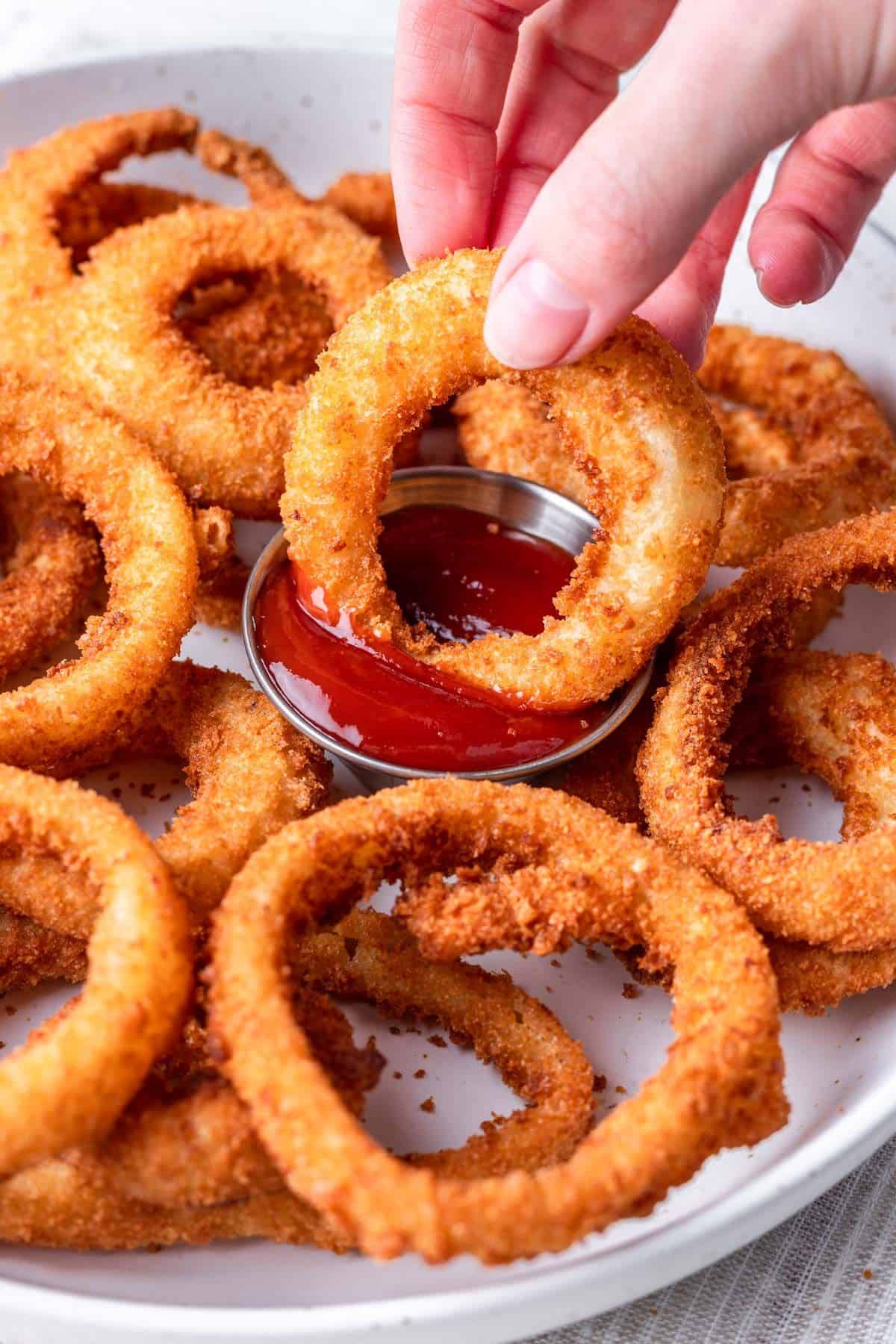 Dunking onion rings in ketchup.