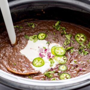 Mexican black bean soup with ladle in crockpot.