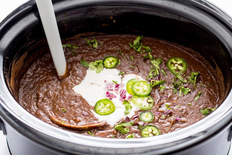 Mexican black bean soup with ladle in crockpot.