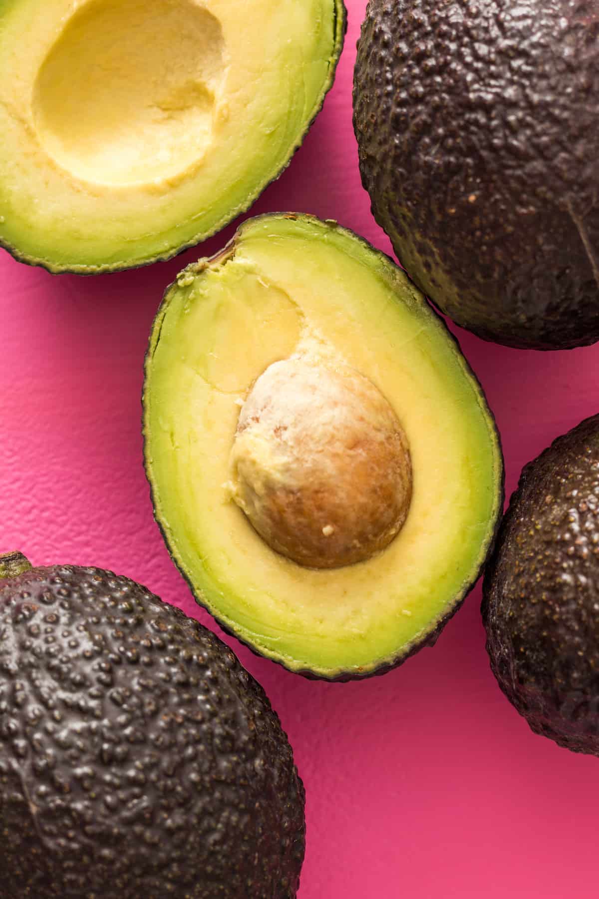Avocados on a pink backdrop.