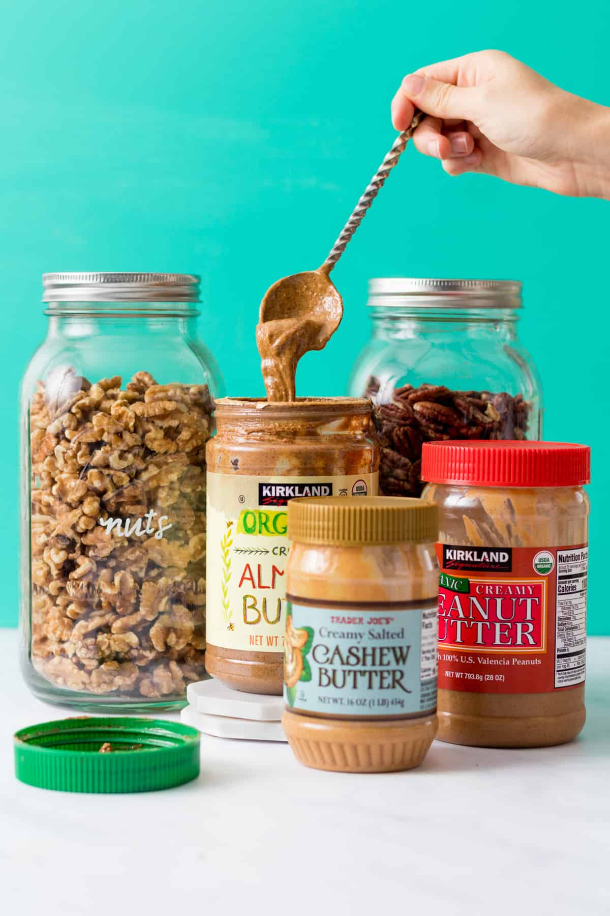 Nuts and nut butters with spoon dipped in almond butter.