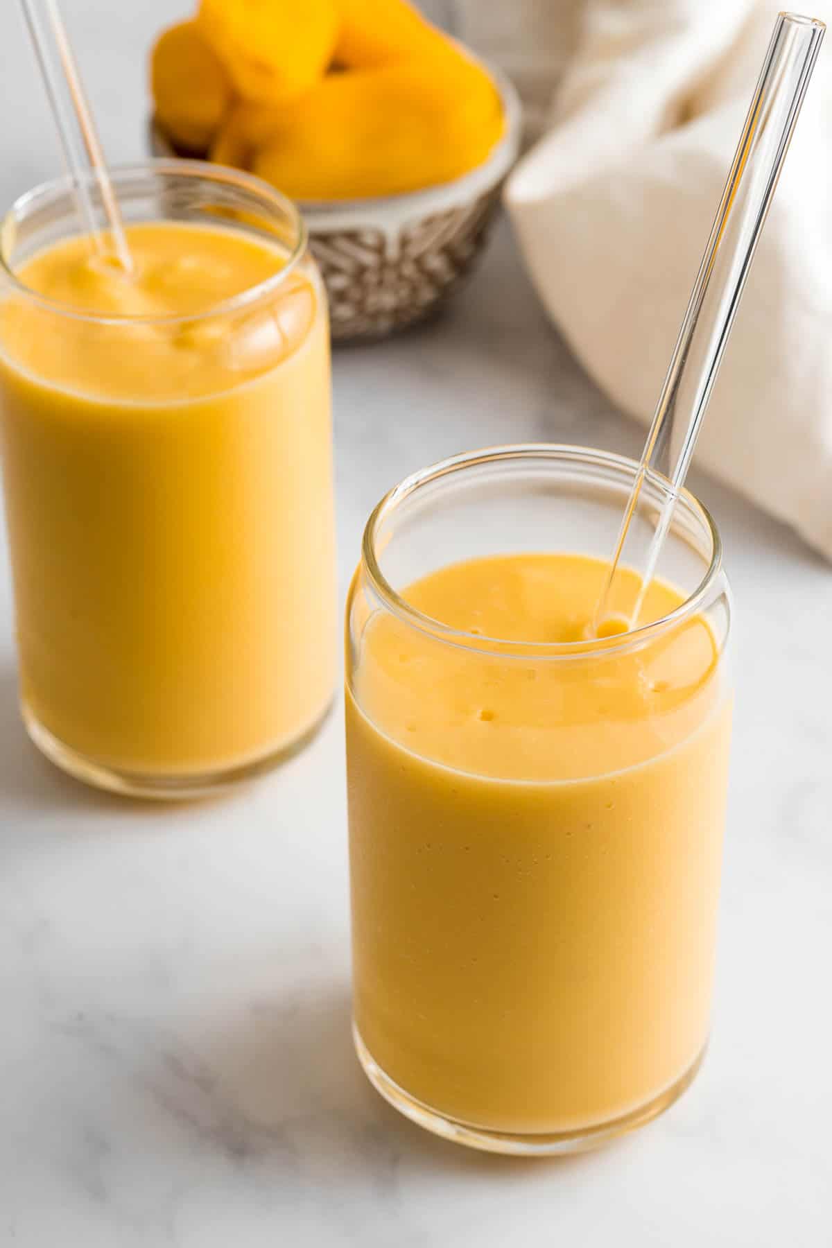 Two jackfruit smoothies in glass with glass straws.